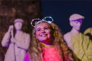 girl with face paint in front of clay statues